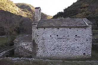 Mur aveugle en pierres surmonté d'un toit.