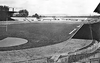 Vue d'un stade vélodrome dont la piste est partiellement couverte par l'ombre du toit d'une tribune.