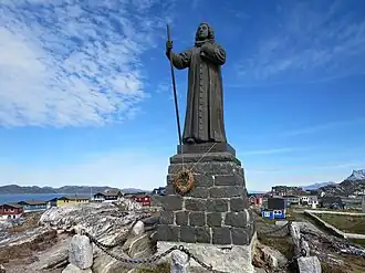 Statue avec des maisons de Nuuk en arrière-plan.