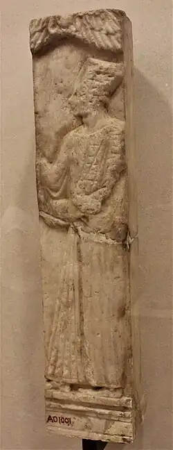 Stèle représentant un personnage de profil levant le bras droit