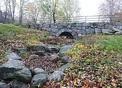 Le ravin du ruisseau et le pont voûté en pierre .