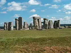 S : talus et fossé du grand cercle initial au premier plan ; cercle et trilithes de sarsen ; Heel Stone au fond à droite.