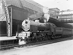 Un train de voyageur à quai dans la gare centrale, remorqué par une locomotive à vapeur de la série 3900