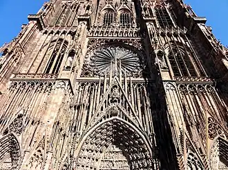 Sur les contreforts, les statues sont placées dans des niches à baldaquin dont les dais élancés sont couronnés d'un oiseau (cigogne ou grue) ou de pinacles, cathédrale Notre-Dame de Strasbourg.