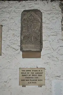 Photographie d'une pierre scuptée accrochée sur un mur