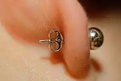 Détail d'une puce d'oreille. Le fermoir papillon est visible à l'arrière du lobe.