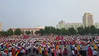 Étudiants dansant lors du 69e anniversaire de la création de la RPDC (en 2017) à l'extérieur du stade Pyongyang Arena.