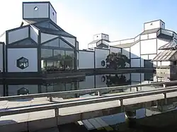 Façades blanches, structure foncée, formes géométriques : triangles, carrés, hexagones, etc. dans un cadre de verdure.