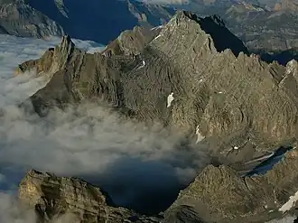 Vue aérienne de la Tête à Pierre Grept depuis le sud-ouest avec la petite ligne de crête s'en éloignant vers la gauche et où se trouvent la Pierre qu'Abotse (pic rocheux), le Gros Sex (à ses pieds devant lui) et le Sex des Branlettes derrière la Pierre qu'Abotse qu'il cache en partie.