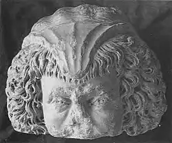 Photo en noir et blanc d'un fragment de tête sculptée : le haut du visage, les cheveux et le sommet du crâne.