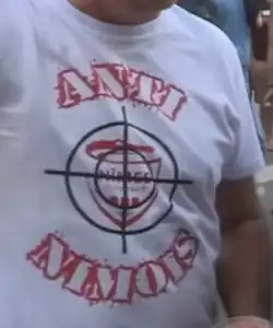 Photographie d'un t-shirt blanc porté par un homme et par des inscriptions rouges.