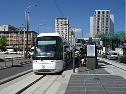 La station Les Flanades dessert le centre commercial éponyme, que l'on voit à droite (toit vert). Ici, la rame no&nbsp;506, en station, en août 2013.