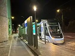 Face avant de la rame TW 20 no&nbsp;4 à la station Cimetière de Saint-Denis en essais nocturnes dans une livrée blanche avec le logo IDFM en bleu sur le flanc. Le nez de la rame est parcouru par un bandeau lumineux blanc