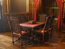 Photographie en couleur d'une table entourée de six chaises en bois.