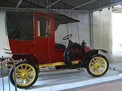 Photographie d'une voiture ancienne rouge, le poste de pilotage ouvert.