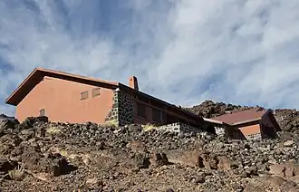 Bâtiment rosâtre dans un paysage rocheux.