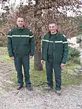 Cadre Technique (commandant) et Ingénieur de l'Agriculture et de l'Environnement (capitaine) de l'Office national des forêts en tenue Numéro 3 au bureau en hiver (chemise tilleul, pull col rond sapin à bande institutionnelle tilleul, veste polaire sapin à bande institutionnelle tilleul et pantalon de travail sapin) en 2009.