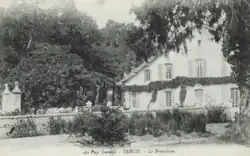 Vue de côté de la façade d'une maison landaise à deux étages.