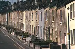 Yellow stone terraced houses alongside a steep road.