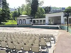 Photographie en couleurs d'une esplanade garnie de rangées de chaises au premier plan, scène au second plan.