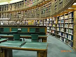 Vue d'une partie de la salle de lecture avec de grandes bibliothèques et des tables de lecture.