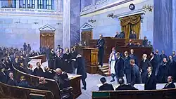 Tableau montrant des hes hommes en costume dans un hémicycle aux murs bleu.