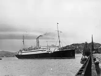 Photographie en noir et blanc d’un navire d’immigrants dans un port.