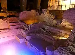 Photographie en couleurs de vestiges de constructions romaines sous lumière artificielle.