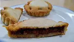 Photographie d'une tielle ouverte, montrant le mélange alimentaire sombre à l'intérieur.