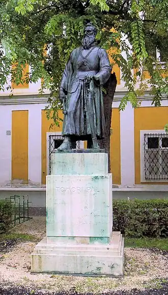 Statue représentant un moine posant armé sur son piédestal simple sur une petite place.