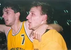 Deux joueurs de profil, l'un avec son bras gauche, enlacant son coéquipier