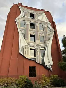 Photographie d'une peinture murale représentant des fenêtres sur un mur en briques rouges
