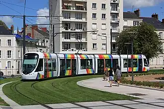 Photographie d'un tramway blanc et arc-en-ciel dans un virage.