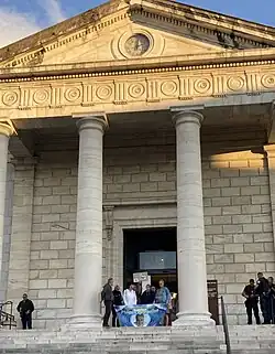 Photographie en couleurs représentant un groupe de personnes sur le perron du tribunal de Pau.