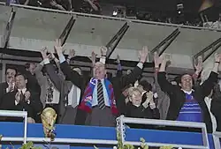 Photo de Jacques Chirac et Michel Platini levant les bras dans une tribune de stade de football.
