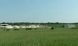 Photographie en couleurs d'excavations dans une paroi laissant la roche à nu sur fond de végétation.
