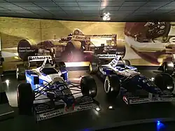 Photo de deux voitures bleues et blanches exposées dans un musée