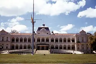 Un homme asiatique et un groupe d'hommes blancs, se tenant debout sur un terrain d'aviation militaire, dans une position de recueillement.