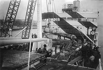 Des canons d'artillerie sur voie ferrée sont ramenés aux États-Unis par le West Hosokie à l'aide d'une grue portuaire.