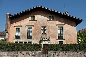 Photographie d'une maison à trois étages et au toit à deux pans, aux murs roses.