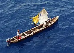 vue en plongée de deux hommes dans une pirogue longue et étroite