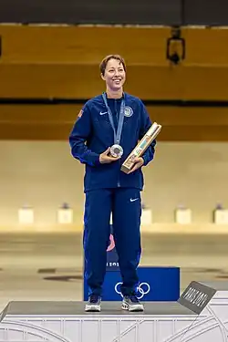 Sagen Maddalena tout de bleu vêtue sur une marche de podium, tenant sa médaille accrochée au cou.