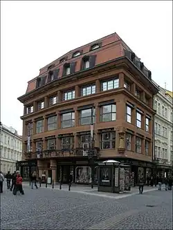 Édifice à dominante brune, donnant sur une zone piétonne, constitué de cinq étages dont deux en combles, possédant des formes rectilignes marquées.