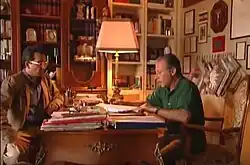 Photographie en couleurs de deux hommes discutant de part et d’autre d’un bureau