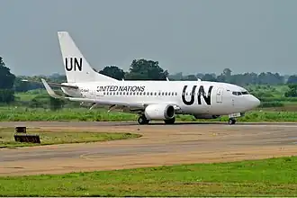 Un Boeing 737, roulant dans une aéroport, opéré par les Nations Unies, étant blanc avec des écritures imposantes "UN" noir