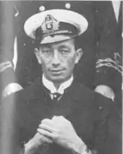 Portrait d'un homme dans la trentaine, en uniforme marin des années 1920-1930, assis avec une expression neutre. Photographie en noir et blanc.