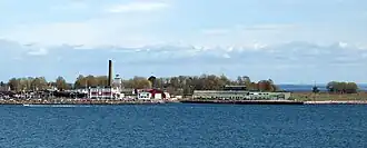 Une vue partielle de Vallø à l’extérieur de Tønsberg, vue de l’ouest. L’église de Vallø peut être vue juste derrière la haute cheminée.