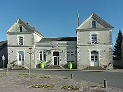 Photographie en couleurs d'un bâtiment composé d'une aile centrale prolongée de part et d'autre par deux pavillons plus hauts.