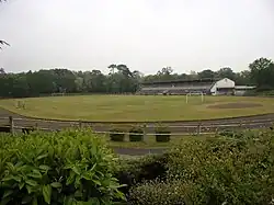 Photographie en couleurs d'un terrain de sports bordé par de longues tribunes couvertes.