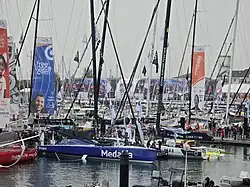 Vu de trois quarts avant, voilier bleu et blanc amarré au ponton.